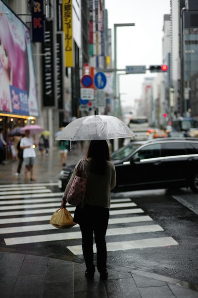 女人拿着雨伞站在基座的车道
